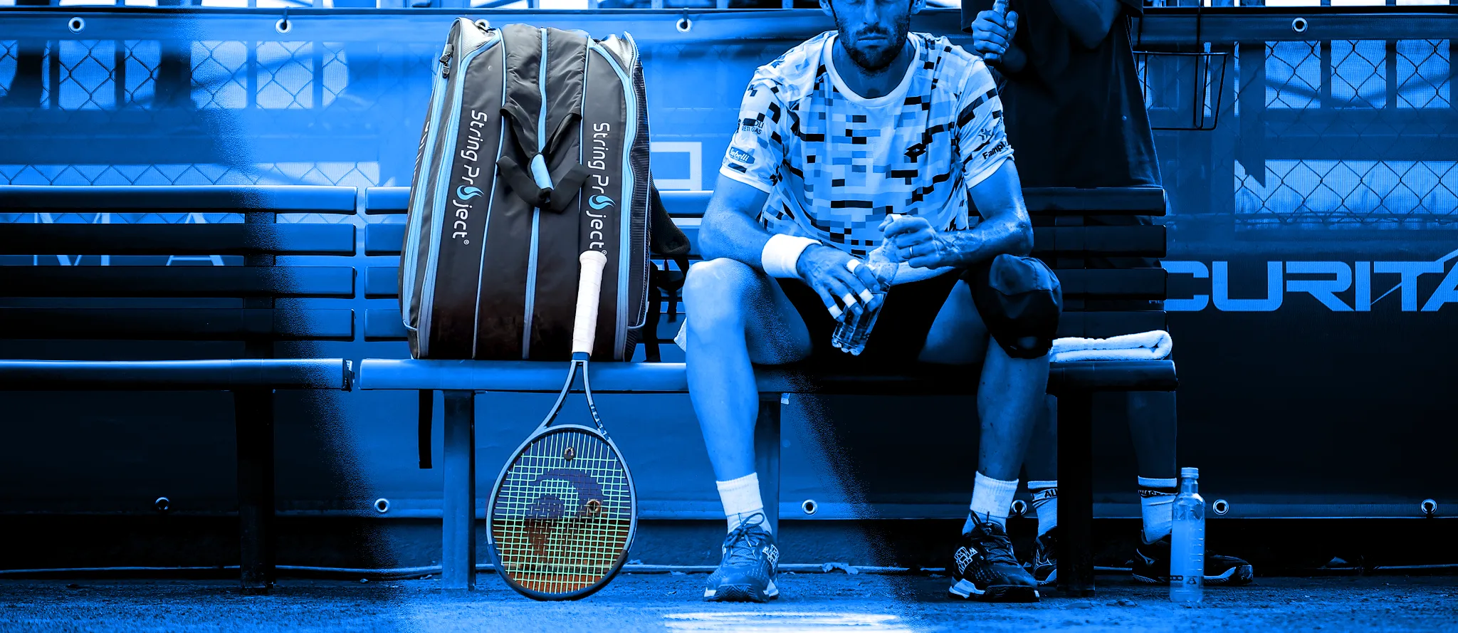 Immagine di sfondo con overlay del giocatore Stefano Travaglia seduto durante il cambio campo